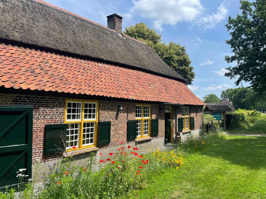 an old brick house with a thatched roof at Domestico Bed & Breakfast in Lage Mierde