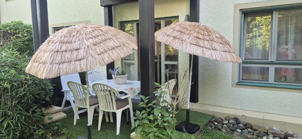 two large straw umbrellas on a table with chairs at Casa Laguna in Oberteuringen