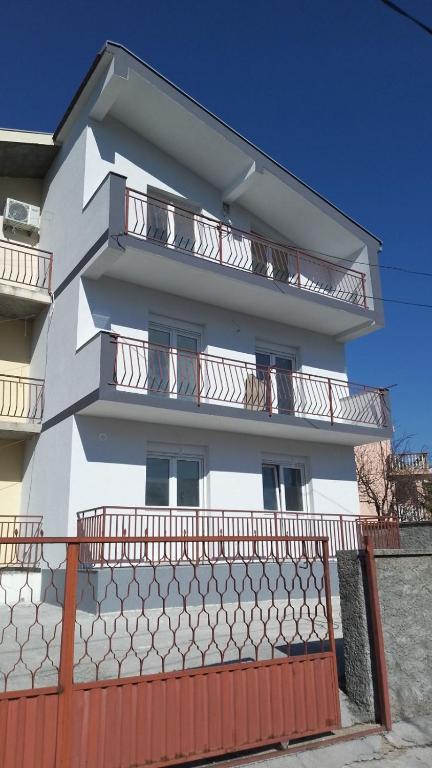 a white building with balconies and a orange fence at Apartmani Rubi 2 in Herceg-Novi