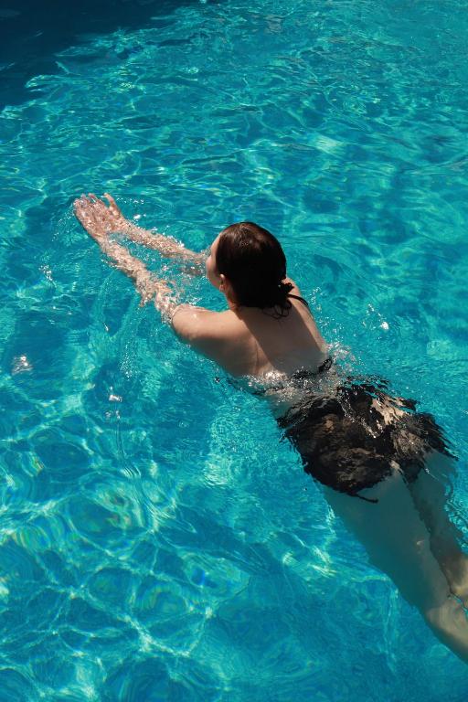 a woman is swimming in the blue water at Перлина Карпат in Pystanʼ