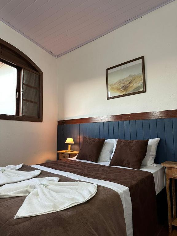 a hotel room with two beds and a window at Pousada Mineira in Ouro Preto