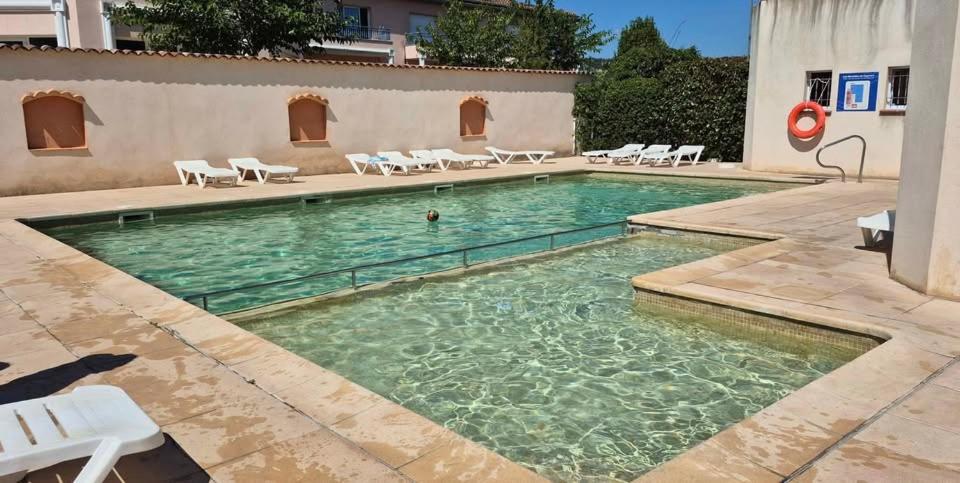 a pool with chairs and a person in the water at maison de vacances in Tourrettes