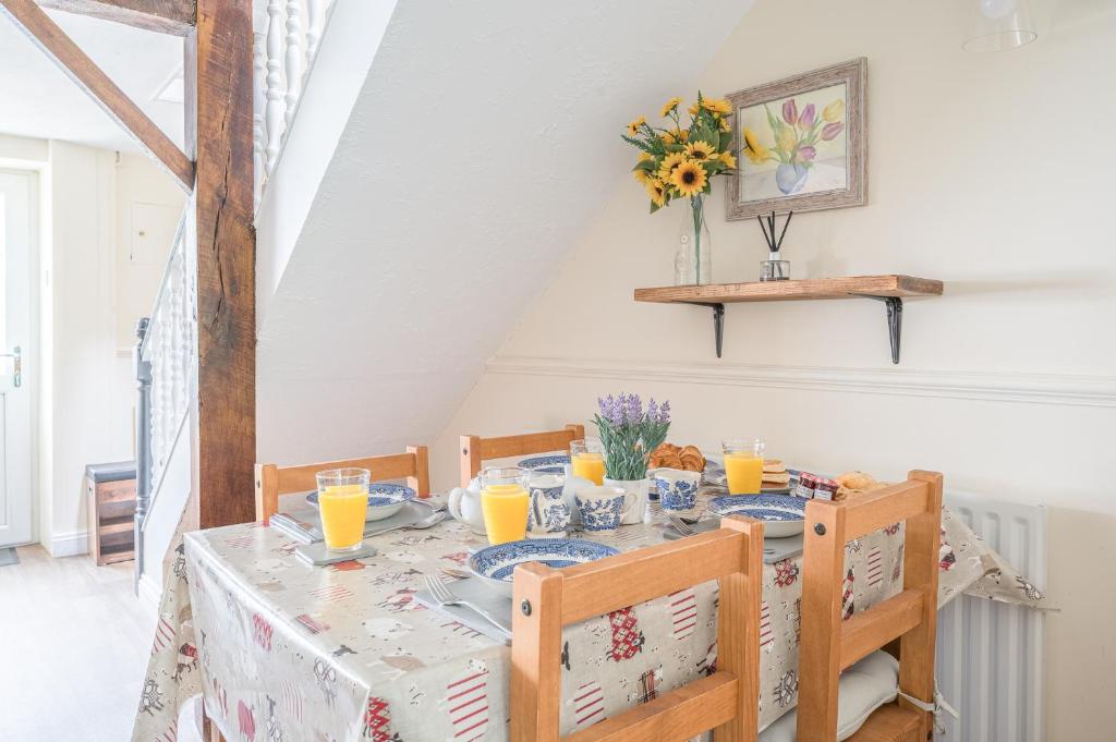 a dining room with a table and chairs with orange juice at Charming Cottage, Lake District in Little Broughton