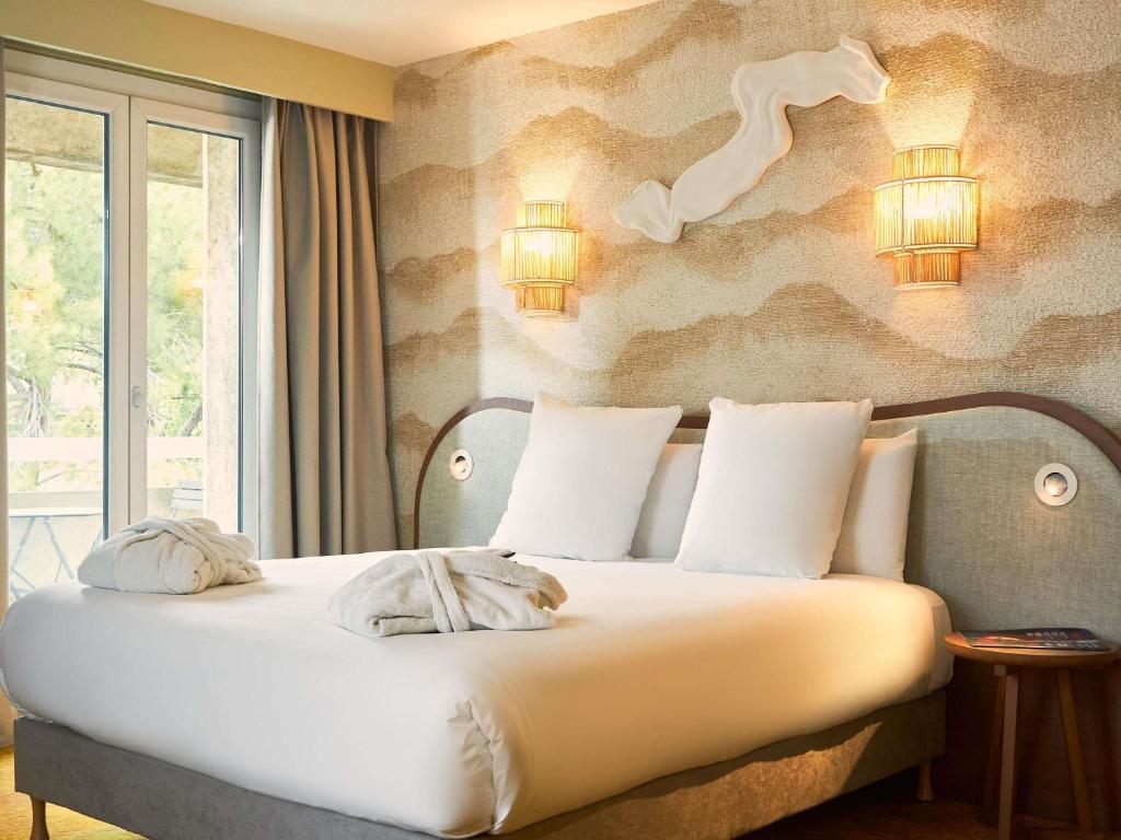 a bedroom with a bed with pillows on it at Mercure Pont d’Avignon Centre in Avignon