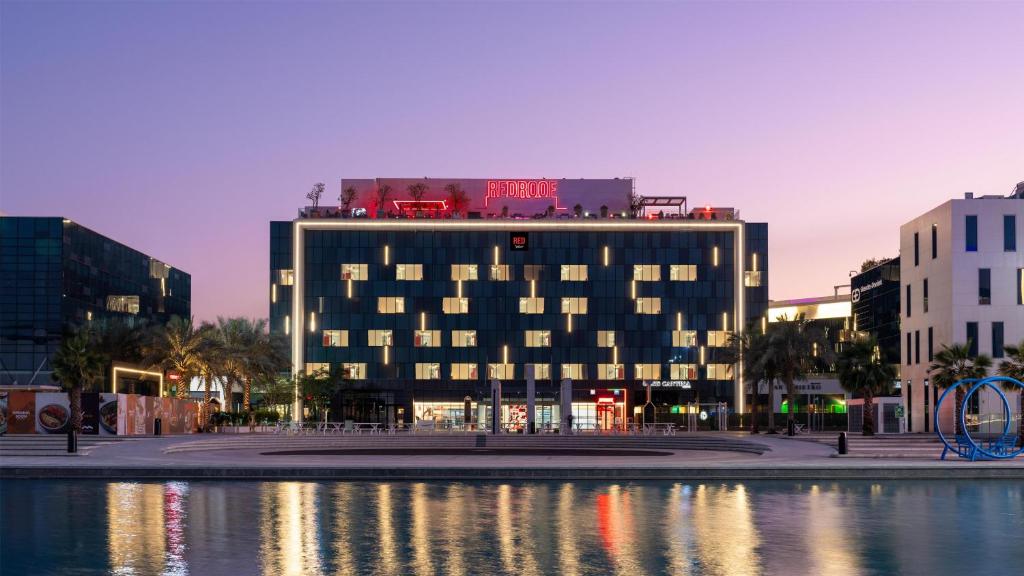 a building with lights on top of it next to a body of water at Radisson RED Dubai Silicon Oasis in Dubai