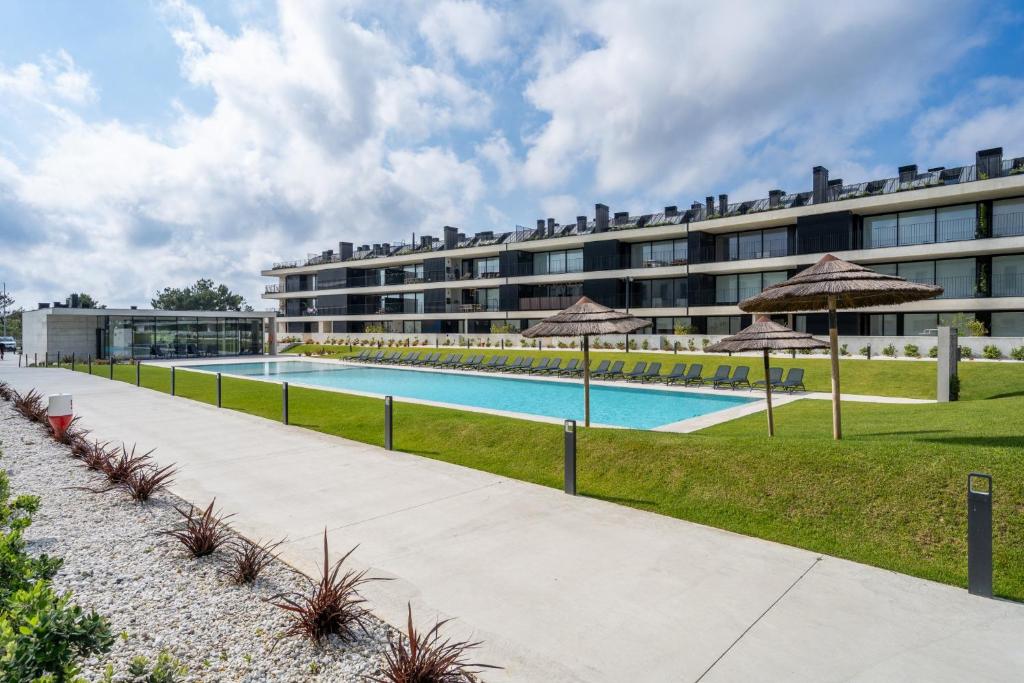a swimming pool with umbrellas in front of a building at Seaside Beach Condo by Minho's Guest in Apúlia