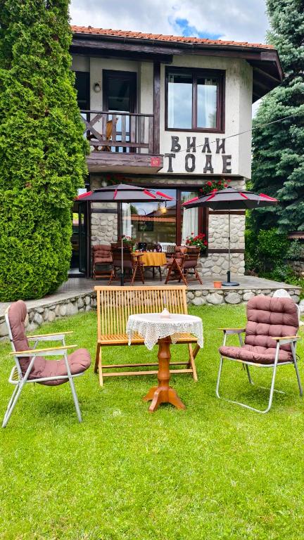 a group of chairs sitting in the grass in front of a house at Premium Villa Tode in Bansko