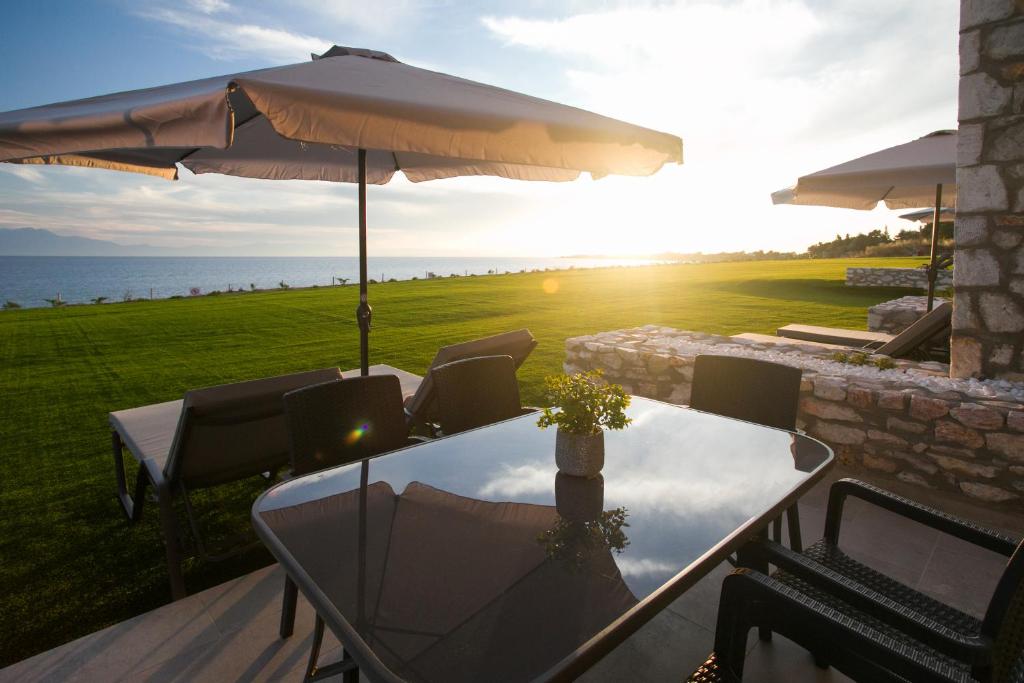 a table and chairs with an umbrella and the ocean at Nine Muses Hospitality in Nea Irakleia