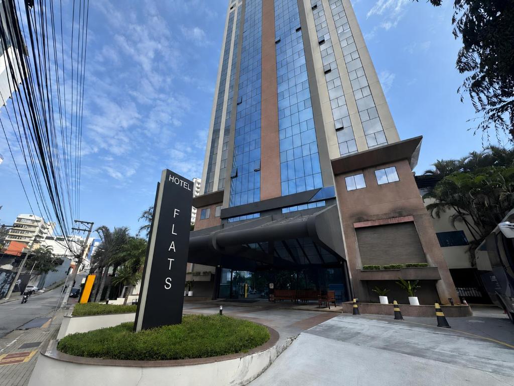a tall building with a sign in front of it at Flat Hotel em Guarulhos in Guarulhos