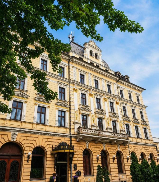 a large yellow building with a tower on top at Hotel President in Bielsko-Biała