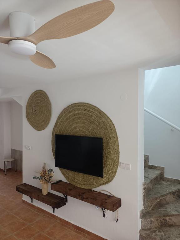 a living room with a flat screen tv and a fan at Picasso Beach House in Oliva