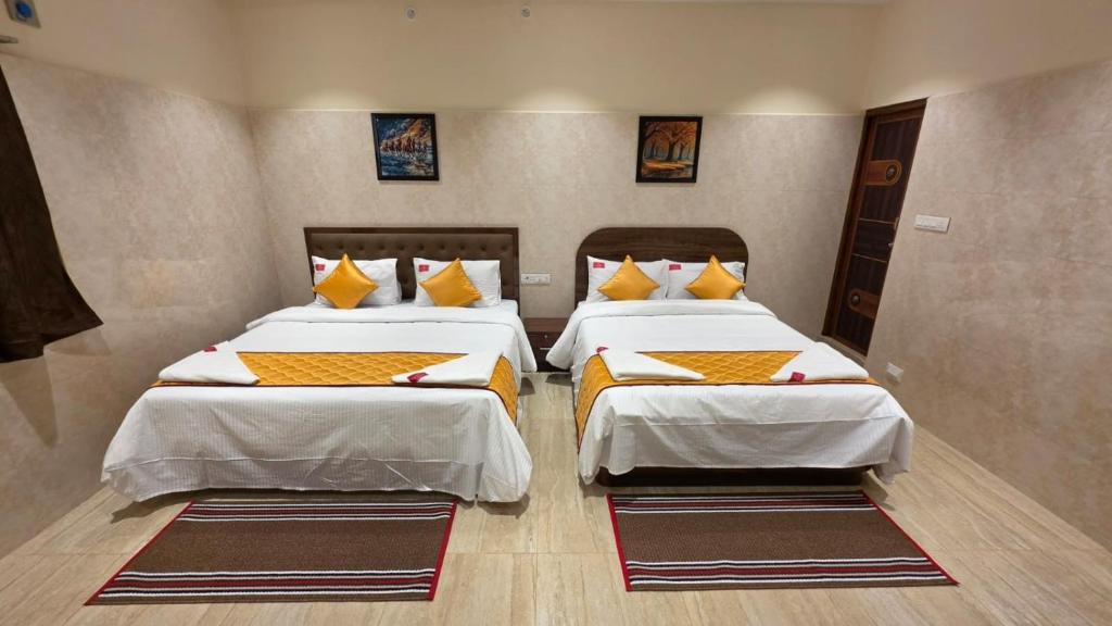 a bedroom with two beds with yellow pillows at Kanchi Crown Residency in Kanchipuram