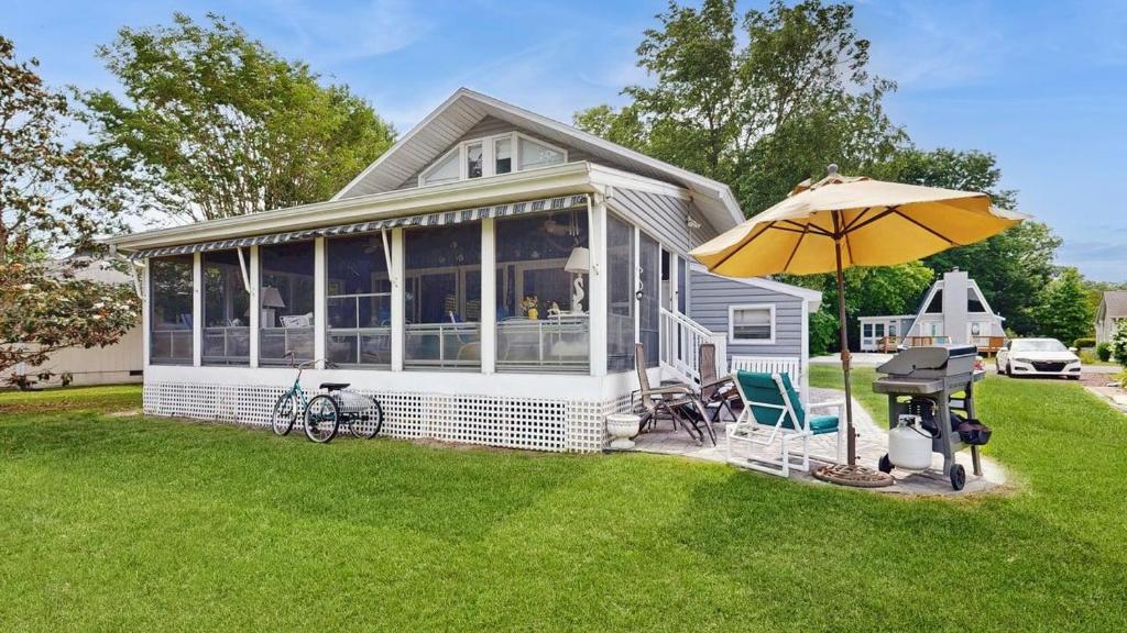 a white house with an umbrella and a table and chairs at Bethany West - 702 Radial Dr in Bethany Beach