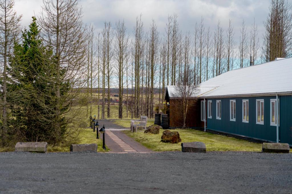a blue building next to a building with trees at Litli Geysir Hotel in Haukadalur