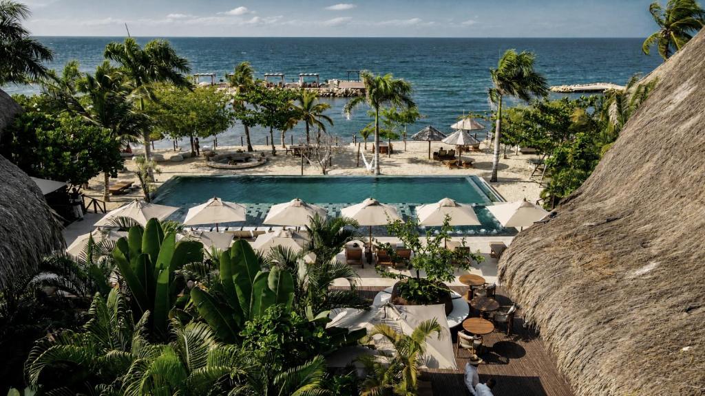 Ein Pool mit Sonnenschirmen und dem Meer im Hintergrund in der Unterkunft Hotel Aimarawa in Coveñas