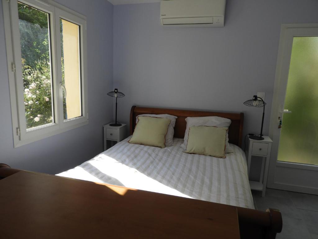 a bedroom with a bed with two pillows and two windows at le studio de la salamandre in Cadillac