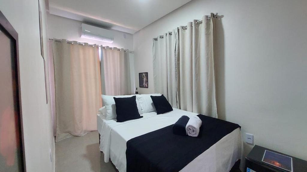 a bedroom with a large bed with black and white sheets at Suítes Rufino in Lençóis