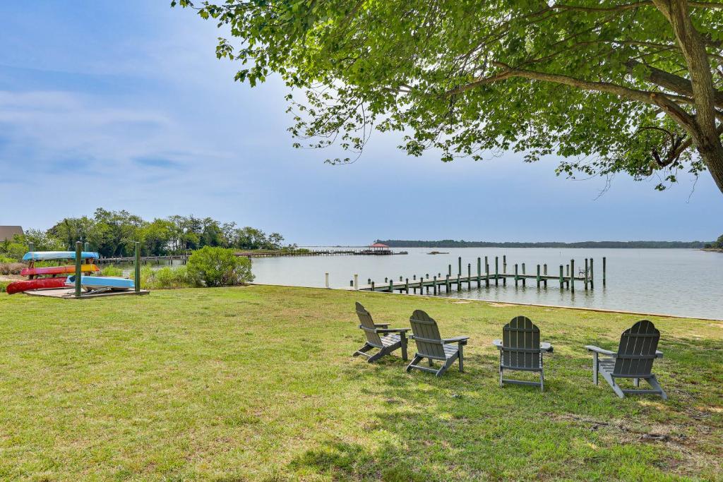a group of chairs sitting on the grass near a lake at Waterfront Home with Large Yard, Dock & Bay View in Heathsville