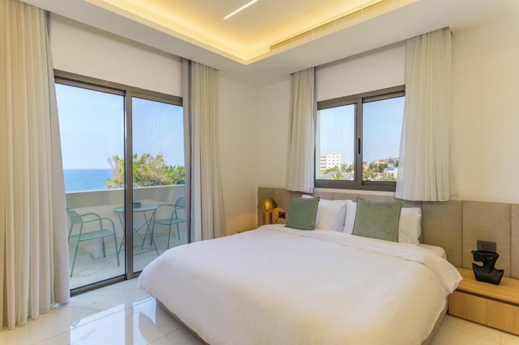 a bedroom with a large bed and large windows at Cavella Apart Hotel in Monsef in Al Ḩulwah
