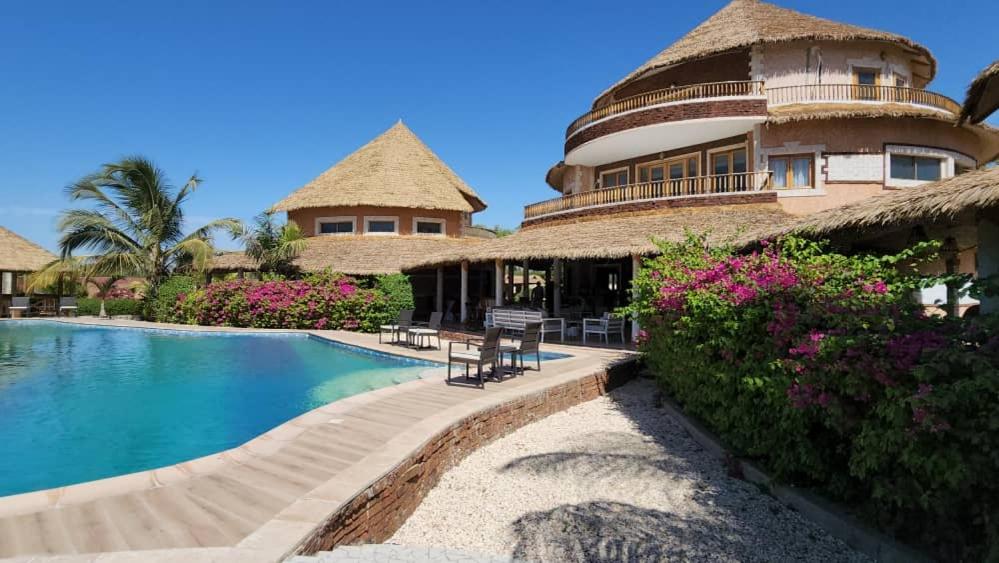 a resort with a swimming pool and a building at Résidence Tina 1 in Ngalou Sessène