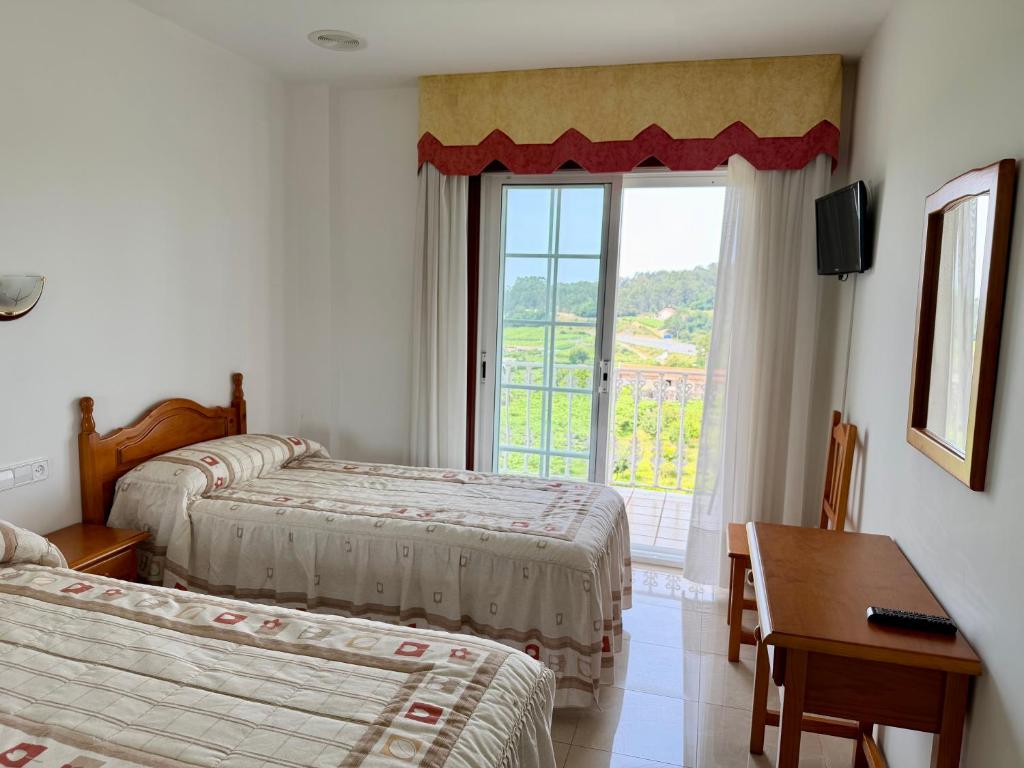 a hotel room with two beds and a window at Casa Rodiño in Meaño