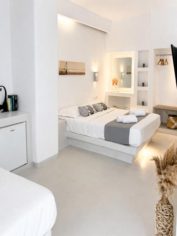 a white bedroom with two beds and a mirror at Fira Centrum White in Fira