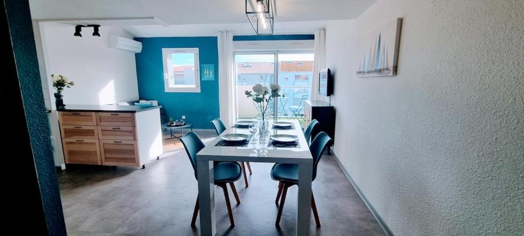 a dining room with a table with blue chairs at L'Ophelia Duplex Dernier étage balcon Centre climatisation in Sète