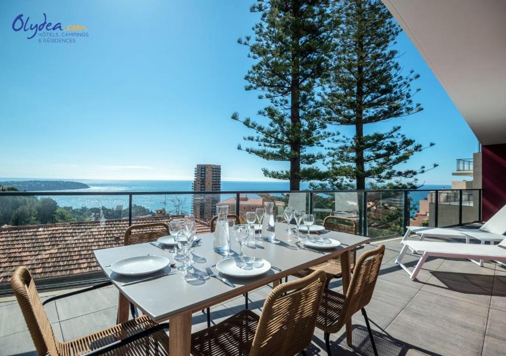 a table on a balcony with a view of the ocean at Olydea Beausoleil in Beausoleil
