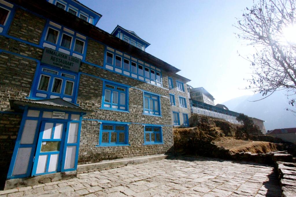 un edificio con ventanas azules y un patio de piedra en Himalayan Lodge en Nāmche Bāzār