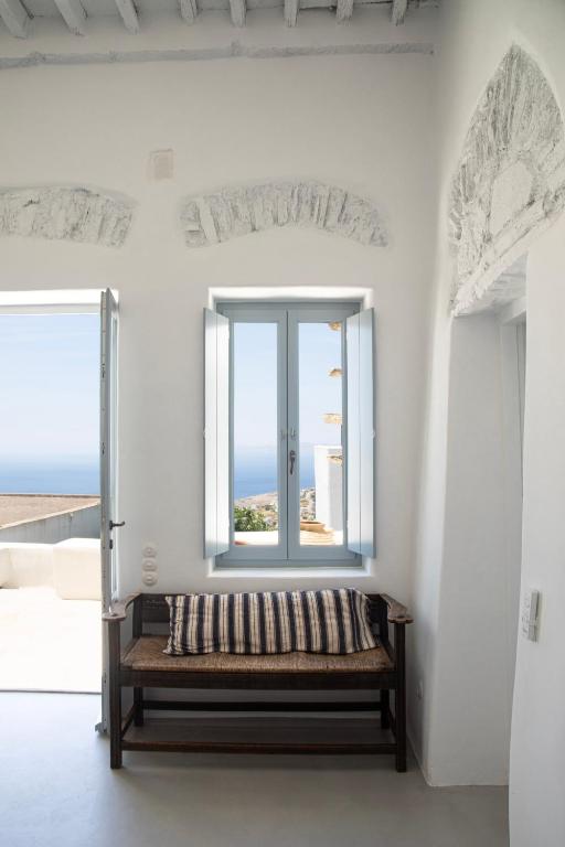 a bench in a white room with a window at DYO Tinos in Triandáros