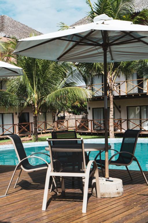 a table and chairs with an umbrella next to a pool at Villas BobZ in Barrinha