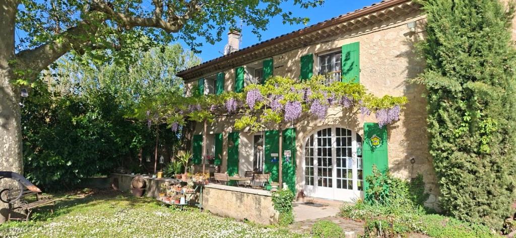 a house with a green door and purple flowers at La Ferme Terre Bio Provence in Lapalud