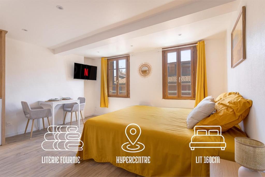 a bedroom with a large bed and a table at Suite du Soleil - Studio - Hypercentre in Narbonne