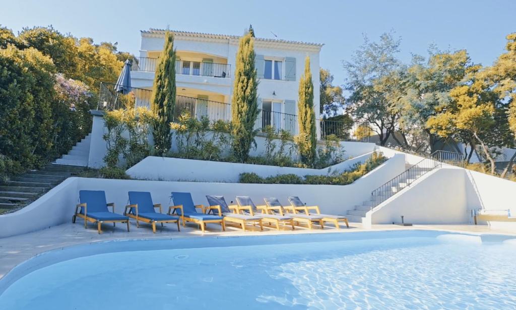 a pool with chairs and a house in the background at Villa JuliMée in Les Issambres