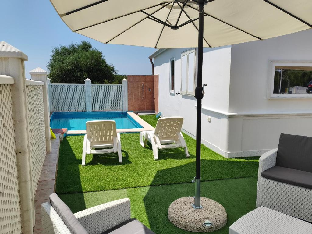 a patio with chairs and an umbrella and a pool at DolceApulia Country House in Conversano