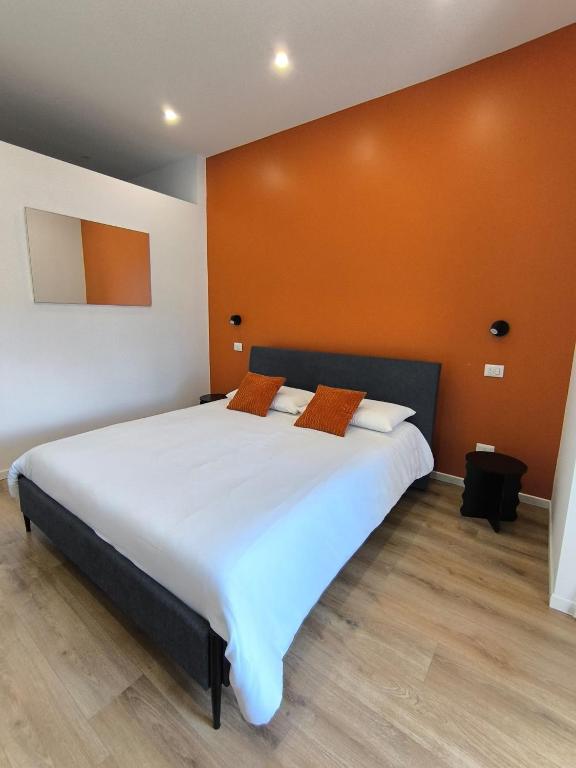 a bedroom with a large white bed with an orange wall at Casa con vista in Ariccia