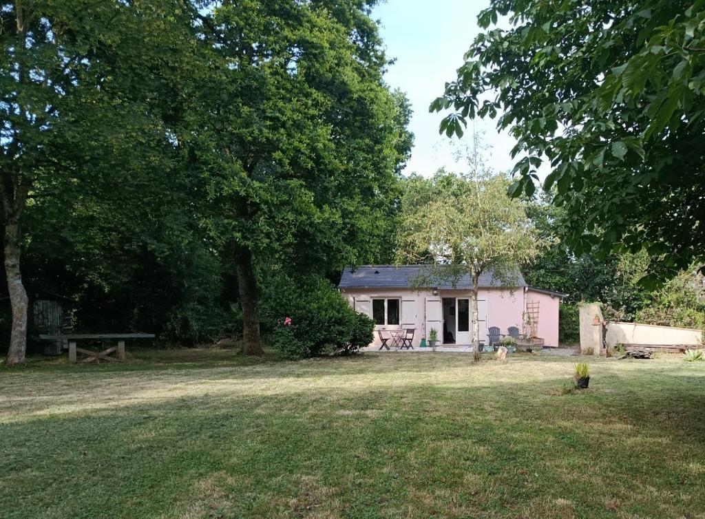 a small white house in the middle of a yard at Maisonnette à la campagne in La Couyère