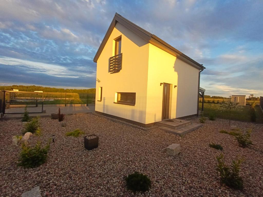 a small white house on a gravel yard at Przystań Łukęcin in Łukęcin
