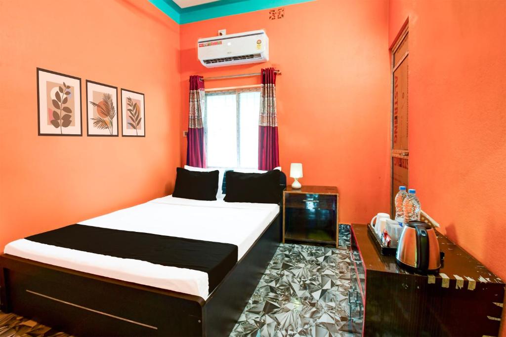a bedroom with orange walls and a bed and a window at Hotel O by OYO ALO Hotel in Phulbāri