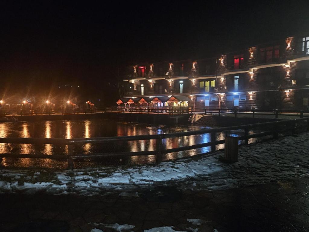 a building at night with lights on the water at DENY INN Funland in Zărneşti