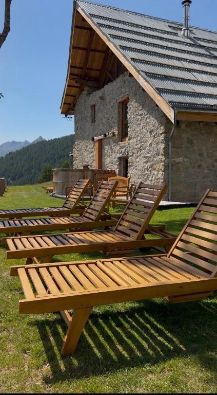 a row of wooden benches in front of a building at Chalets d alpage 5 étoiles la chabane in Orcières