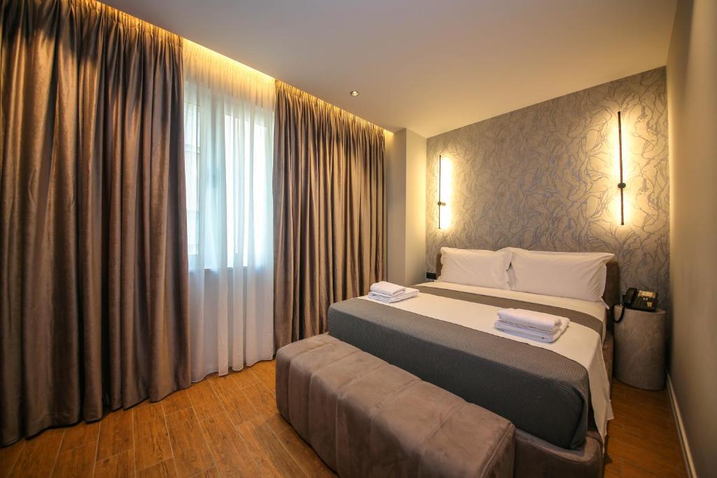 a bedroom with a large bed and a large window at Comfort Boutique Hotel in Tirana