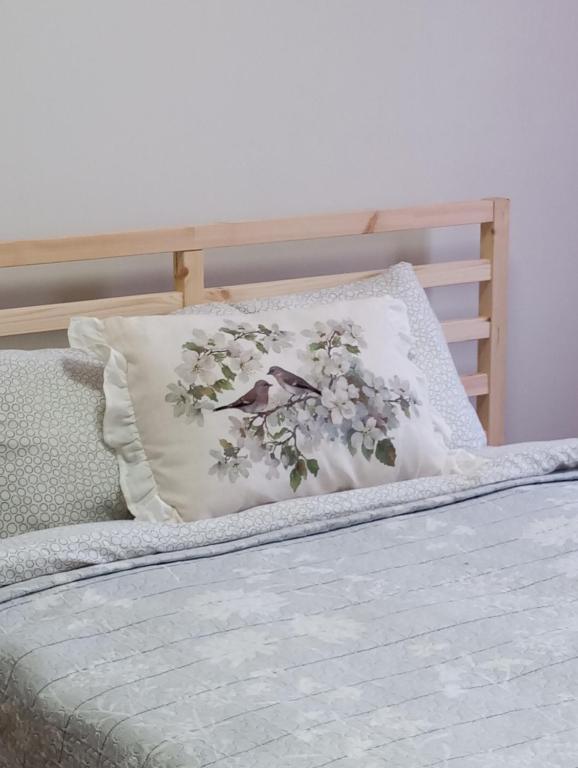a bed with a pillow with flowers on it at Saulespuķe-Kuldīgā in Kuldīga