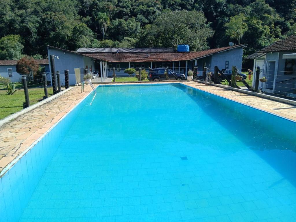 a large blue swimming pool with a house in the background at sitio Ibiúna in Ibiúna