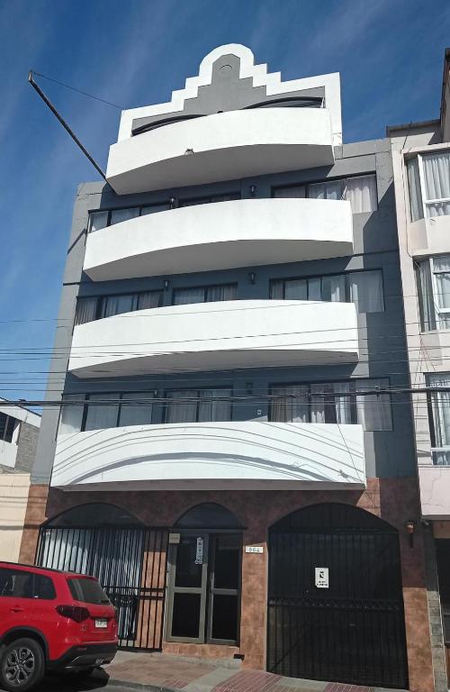 a building with a red car parked in front of it at Apart Hotel Astore in Antofagasta