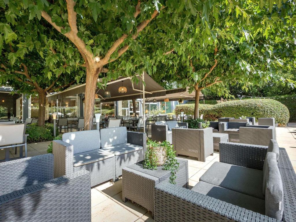 a patio with chairs and tables and trees at Mercure Cavaillon in Cavaillon