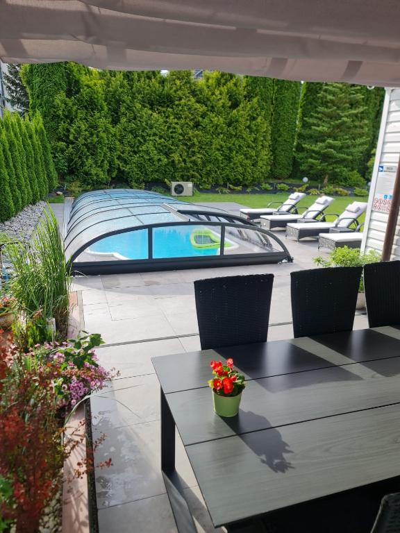 a patio with a table and chairs and a swimming pool at APARTAMENT POD ŚLIWKAMI in Krynica Zdrój