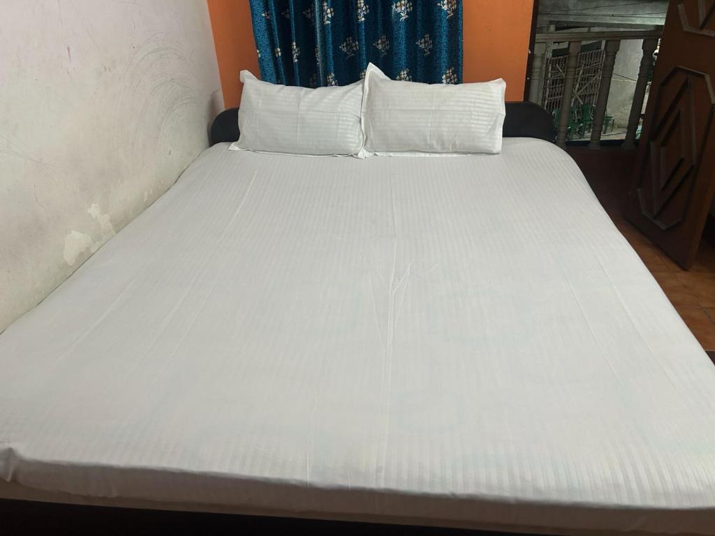 a large white bed with white sheets and pillows at Priyadarshi Hotel in New Digha