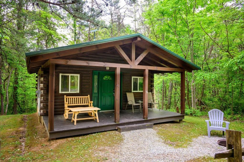 a wooden cabin with a green door in the woods at Wren's Nest in Logan