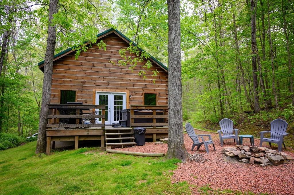a log cabin in the woods with two chairs at Bear Hollow in Logan